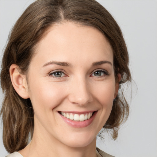 Joyful white young-adult female with medium  brown hair and grey eyes