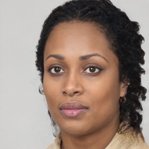 Joyful black young-adult female with long  black hair and brown eyes