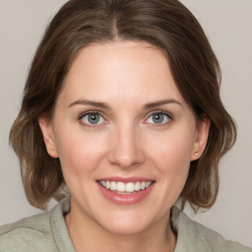 Joyful white young-adult female with medium  brown hair and grey eyes