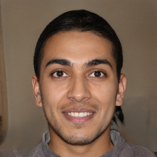 Joyful latino young-adult male with short  brown hair and brown eyes