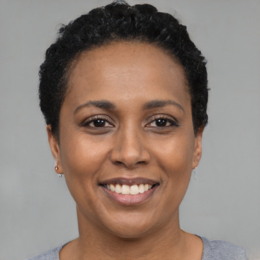 Joyful black young-adult female with short  black hair and brown eyes
