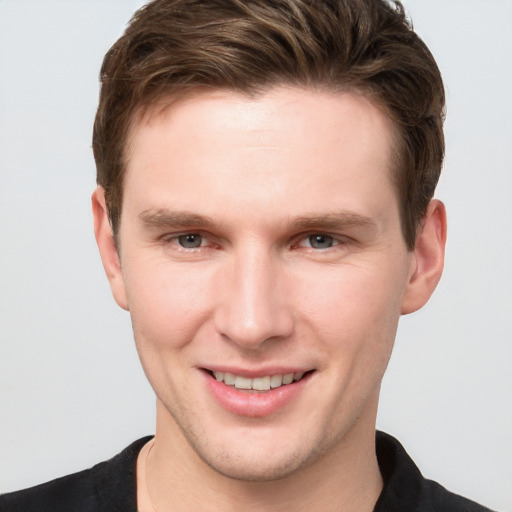 Joyful white young-adult male with short  brown hair and grey eyes