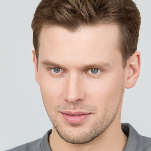 Joyful white young-adult male with short  brown hair and grey eyes