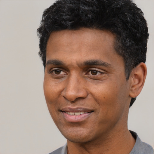 Joyful black adult male with short  black hair and brown eyes
