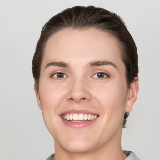 Joyful white young-adult female with short  brown hair and grey eyes