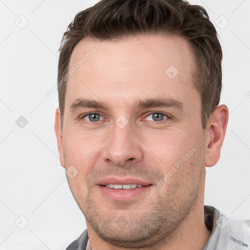 Joyful white young-adult male with short  brown hair and grey eyes