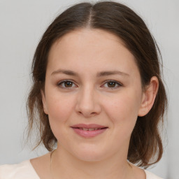 Joyful white young-adult female with medium  brown hair and grey eyes