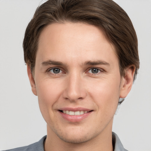 Joyful white young-adult male with short  brown hair and grey eyes