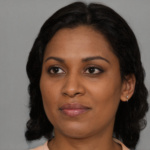 Joyful black young-adult female with long  brown hair and brown eyes