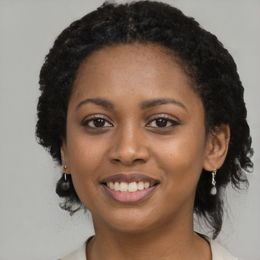 Joyful black young-adult female with long  black hair and brown eyes