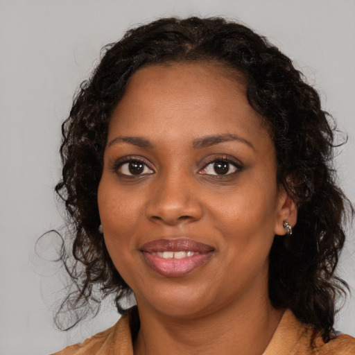 Joyful black young-adult female with long  brown hair and brown eyes