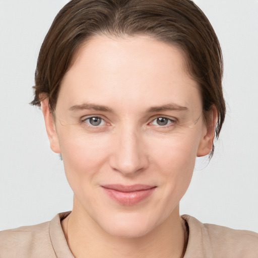 Joyful white young-adult female with medium  brown hair and grey eyes