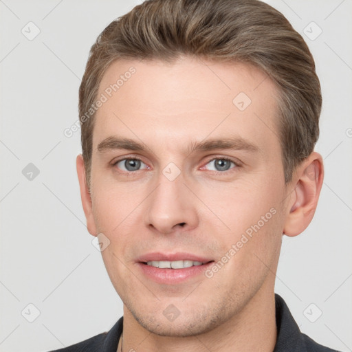 Joyful white young-adult male with short  brown hair and grey eyes