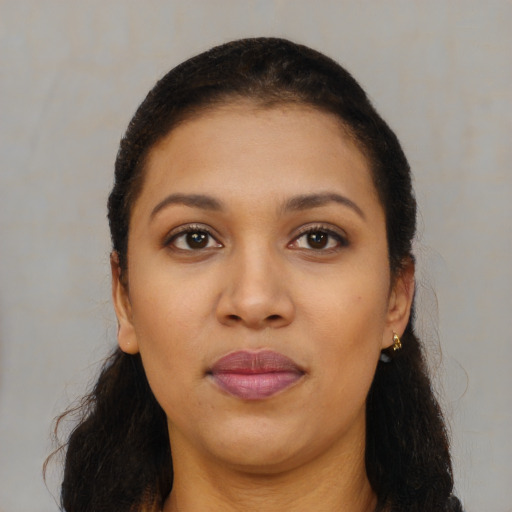 Joyful black young-adult female with long  brown hair and brown eyes