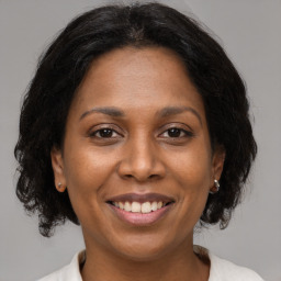 Joyful black adult female with medium  brown hair and brown eyes