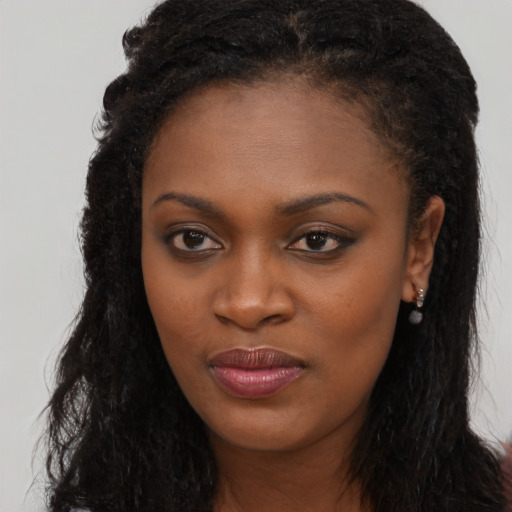 Joyful black young-adult female with long  brown hair and brown eyes