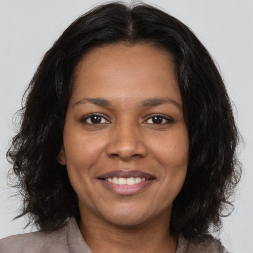 Joyful black young-adult female with medium  brown hair and brown eyes