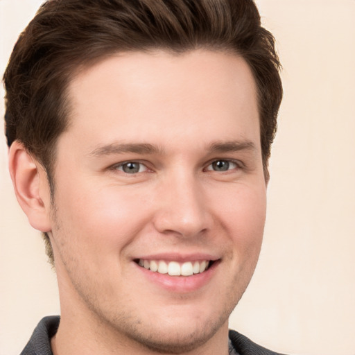 Joyful white young-adult male with short  brown hair and grey eyes