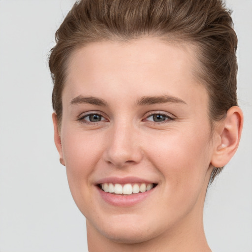 Joyful white young-adult female with short  brown hair and grey eyes