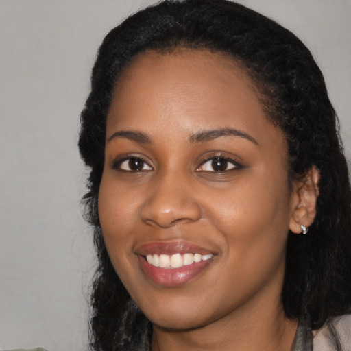 Joyful black young-adult female with long  black hair and brown eyes