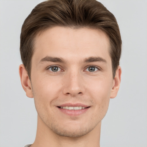 Joyful white young-adult male with short  brown hair and grey eyes