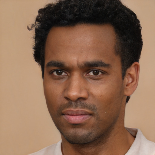 Joyful black young-adult male with short  black hair and brown eyes
