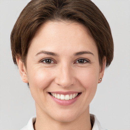 Joyful white young-adult female with short  brown hair and grey eyes