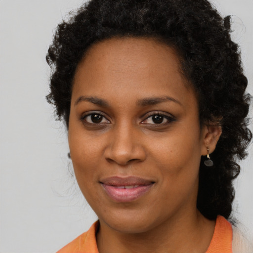 Joyful black young-adult female with long  brown hair and brown eyes