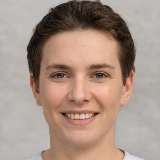 Joyful white young-adult female with short  brown hair and grey eyes