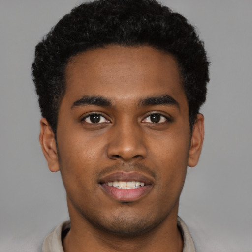 Joyful black young-adult male with short  black hair and brown eyes