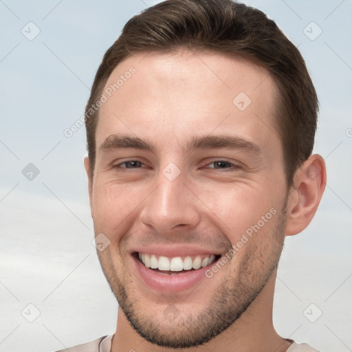 Joyful white young-adult male with short  brown hair and grey eyes