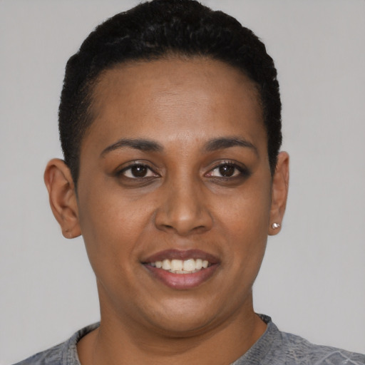 Joyful black young-adult female with short  black hair and brown eyes