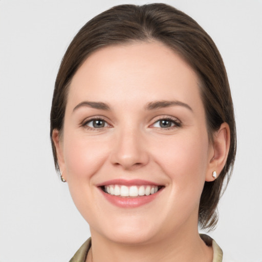 Joyful white young-adult female with medium  brown hair and grey eyes