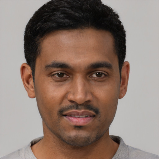 Joyful latino young-adult male with short  black hair and brown eyes