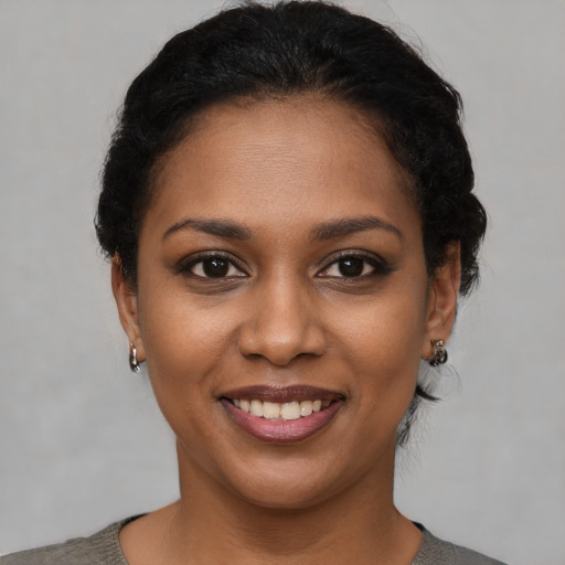 Joyful black young-adult female with short  black hair and brown eyes