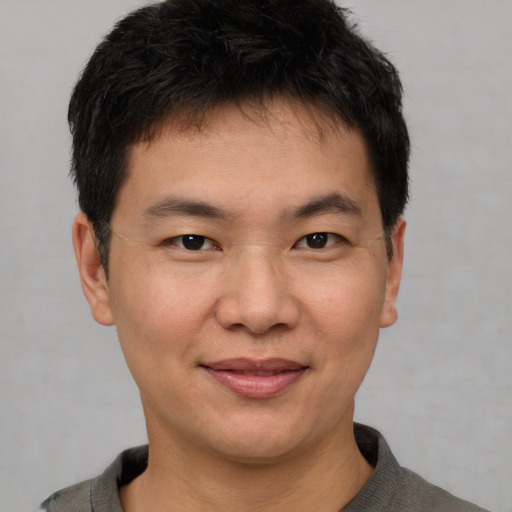 Joyful asian young-adult male with short  brown hair and brown eyes