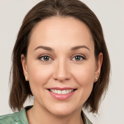 Joyful white young-adult female with medium  brown hair and grey eyes