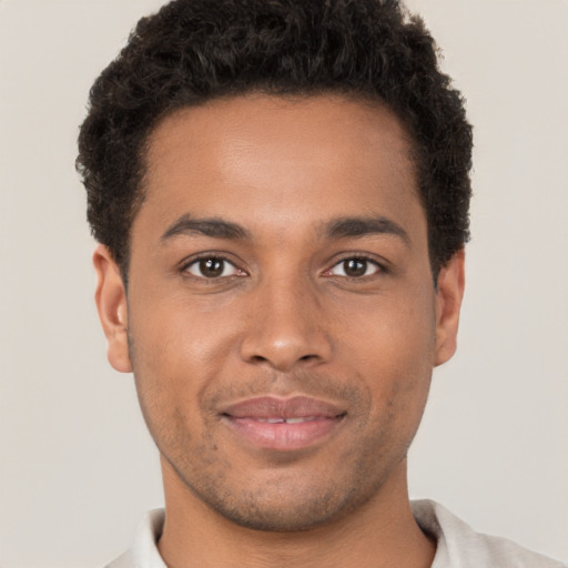 Joyful black young-adult male with short  brown hair and brown eyes