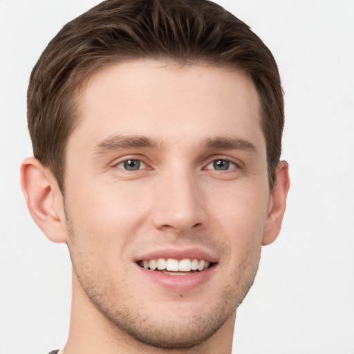 Joyful white young-adult male with short  brown hair and grey eyes