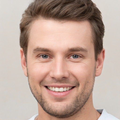 Joyful white young-adult male with short  brown hair and grey eyes