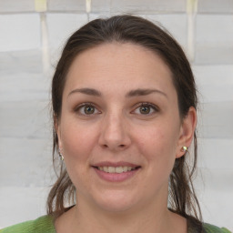 Joyful white young-adult female with medium  brown hair and green eyes