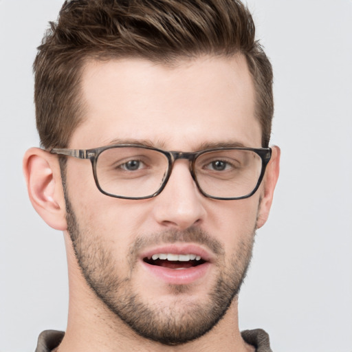 Joyful white young-adult male with short  brown hair and grey eyes