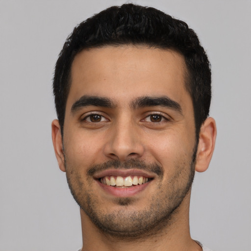 Joyful latino young-adult male with short  black hair and brown eyes