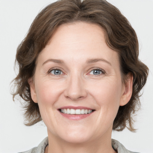 Joyful white adult female with medium  brown hair and grey eyes