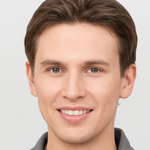 Joyful white young-adult male with short  brown hair and grey eyes