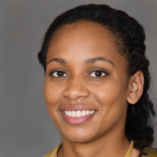 Joyful black young-adult female with long  black hair and brown eyes