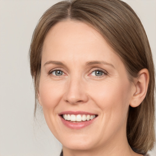 Joyful white adult female with medium  brown hair and grey eyes