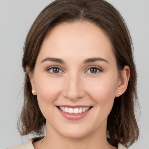 Joyful white young-adult female with medium  brown hair and grey eyes