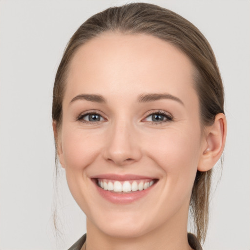 Joyful white young-adult female with medium  brown hair and grey eyes