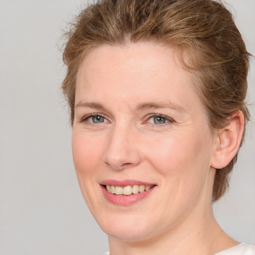 Joyful white young-adult female with medium  brown hair and blue eyes